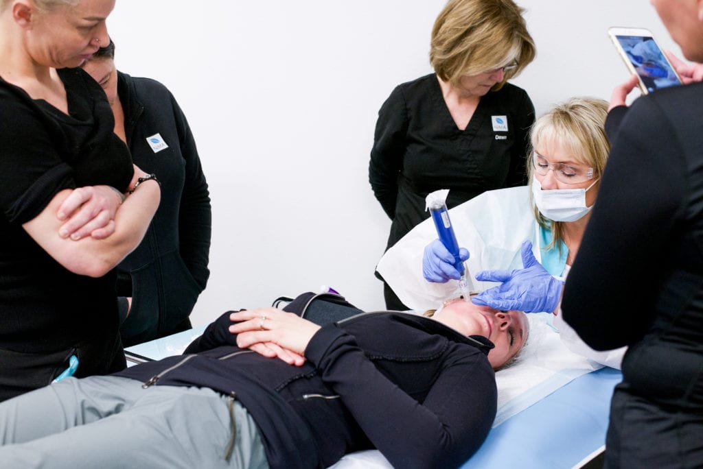 Several students watching teacher perform microneedling